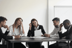 A group of unhappy and stressed employees in a conference room